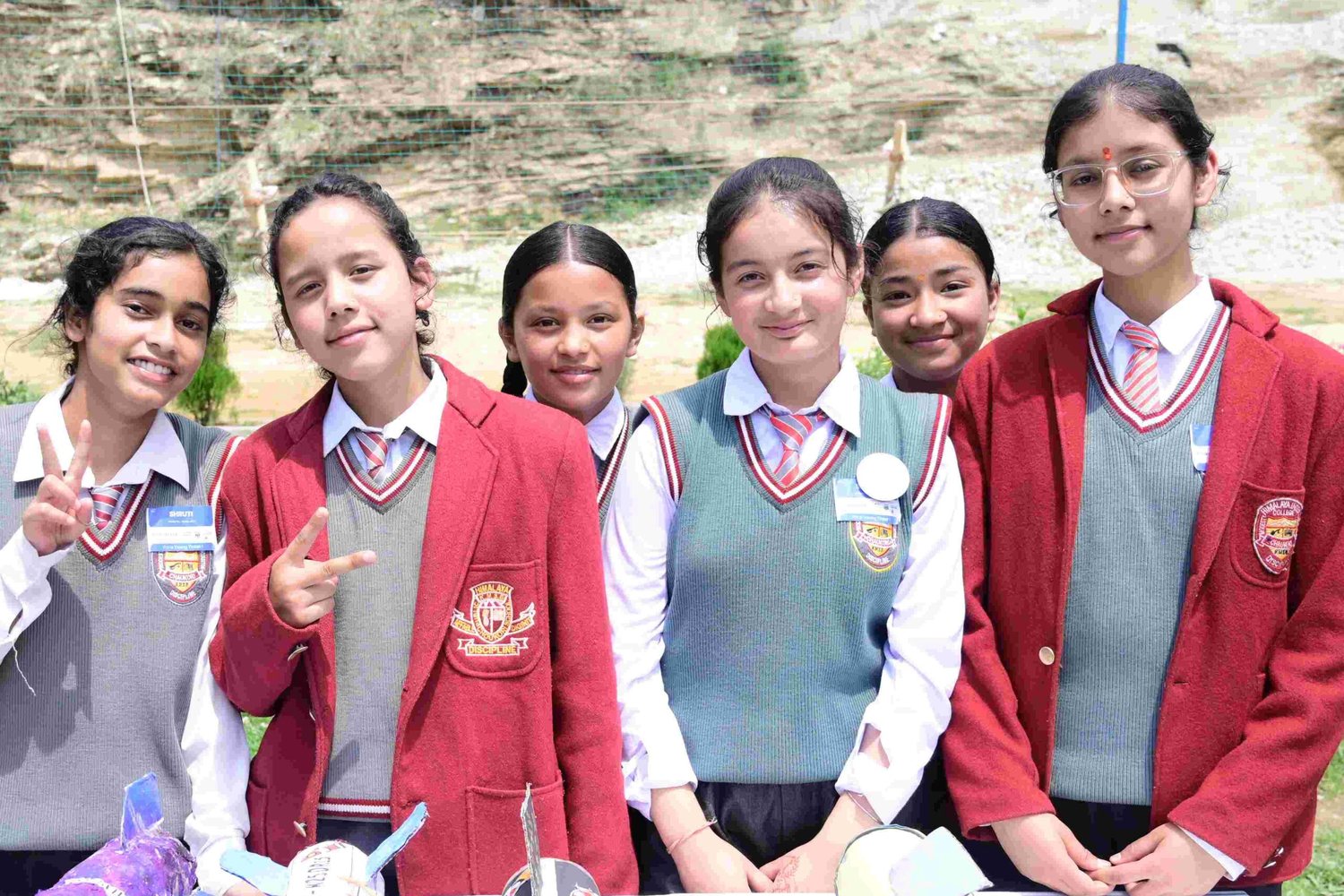 Six smiling school students standing behind the paper rockets they built at a Young Tinker event.